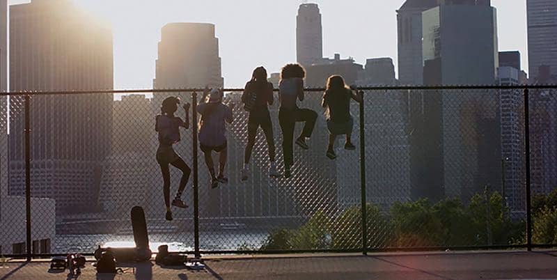 the cast of Skate Kitchen climb a fence