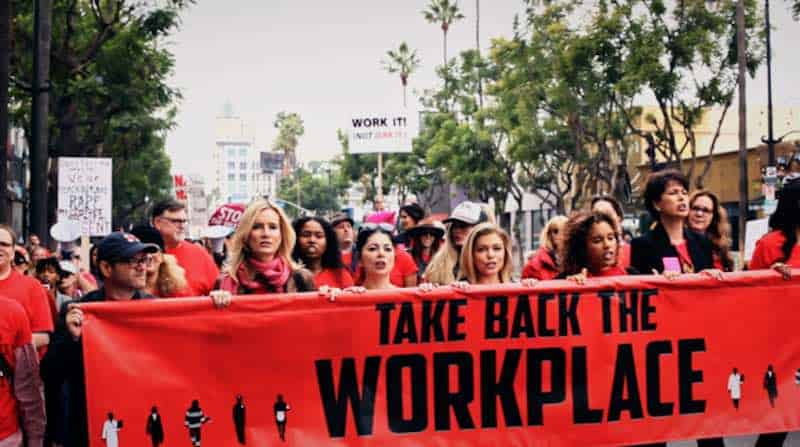 Women marching with "Take Back the Workplace" on a banner