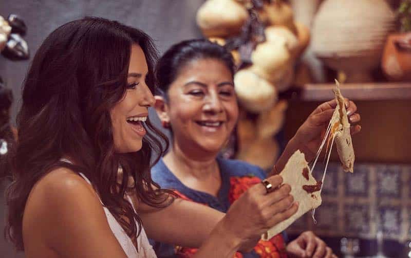 Eva Longoria and a cook sample a recipe in Searching for Mexico